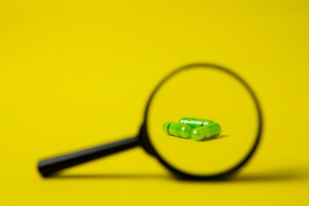Lupa ao lado de um conjunto de comprimidos verdes sobre uma superfície amarela.